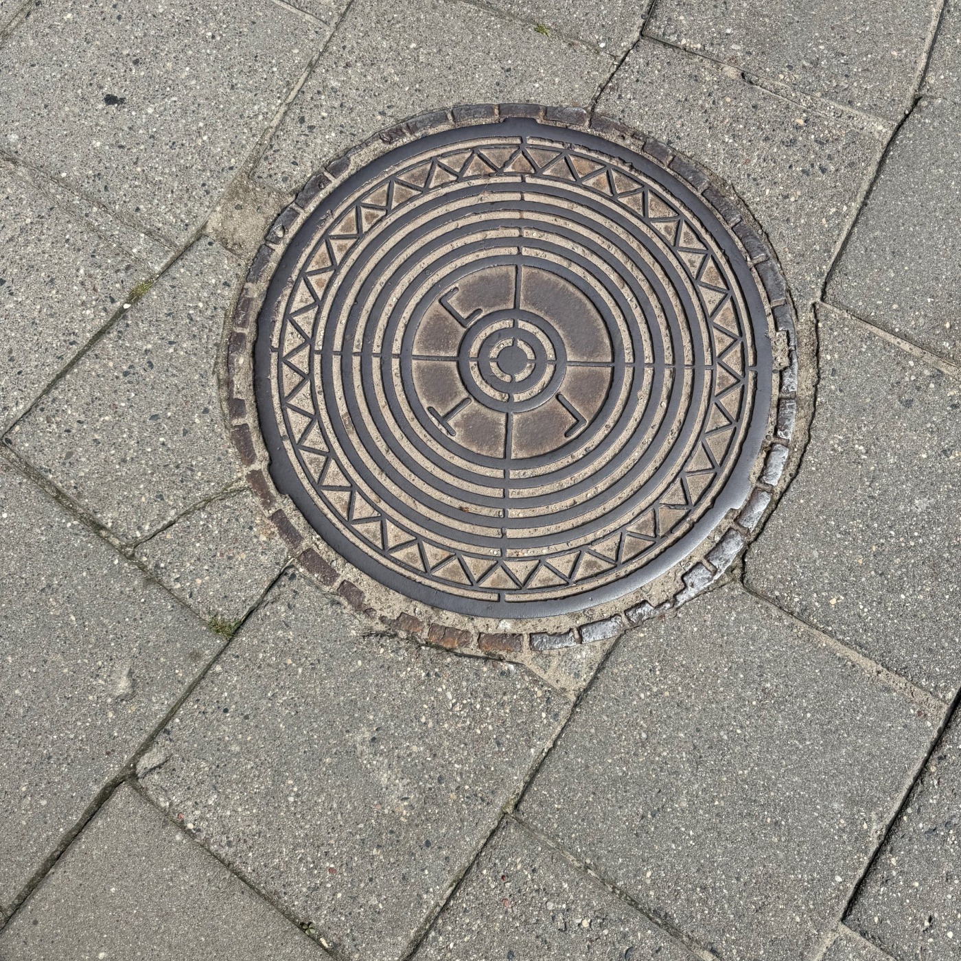 Centrální kruhový vzor s radiálními a koncentrickými liniemi dominuje tomuto exempláři městské infrastruktury, obklopené — CoverSpot