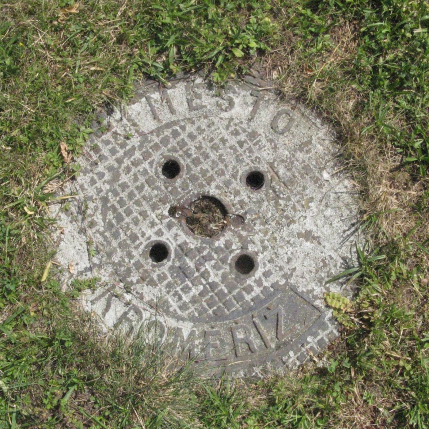 Mřížkovaný vzor dominuje povrchu tohoto exempláře městské infrastruktury, skrze zvětralé nápisy nenápadně odhalující jeh — CoverSpot