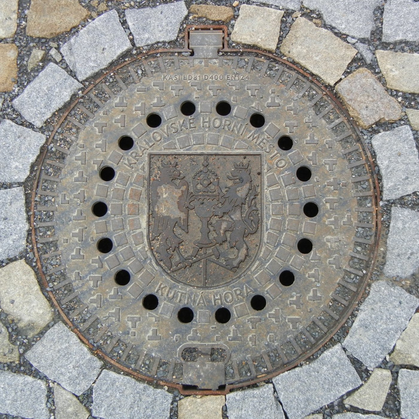 Uprostřed kruhového litinového exempláře dominuje detailní erb, obklopený nápisy odkazujícími na historické město. Okoln in Czechia — CoverSpot