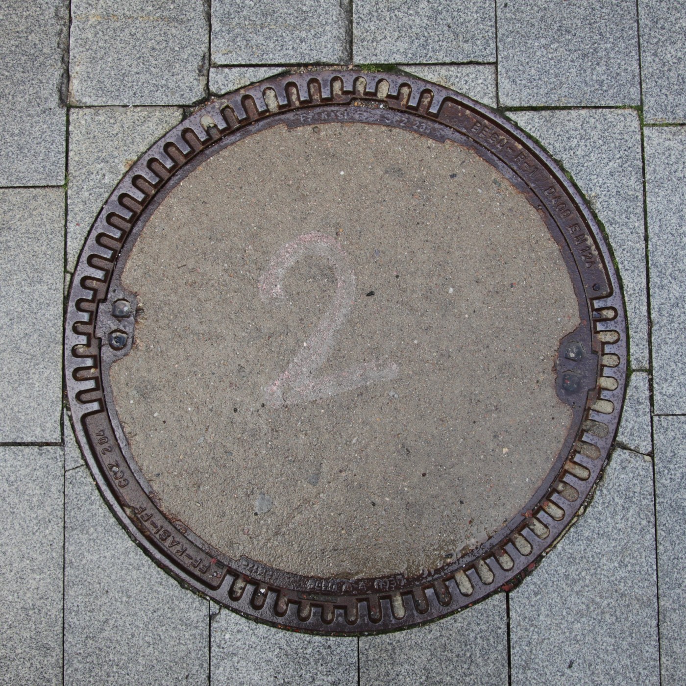 Na šedém betonovém povrchu je křídou načmárána cifra '2', což naznačuje buď pořadové číslo, nebo snad jen dětskou hru. R in Hradec Králové, Czechia — CoverSpot