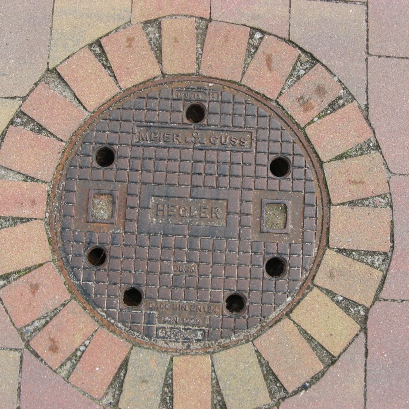 Robustní mřížkový vzor dominuje centrální ploše tohoto kruhového exempláře, obklopený zřetelnými nápisy 'MEIER & GUSS' a in Binzen, Germany — CoverSpot