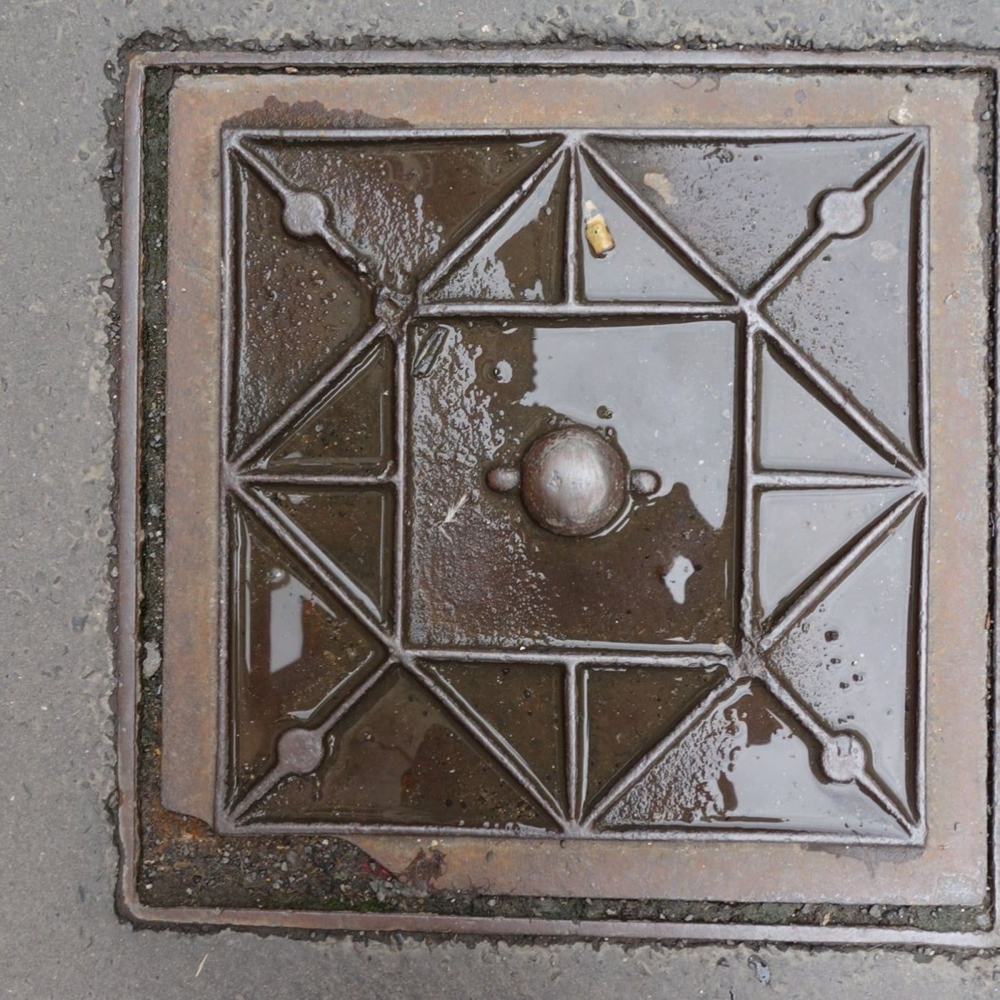 Na tmavě rezavém povrchu se zrcadlí kalná voda, která vyplňuje hluboké geometrické vzory tvořené čtverci a trojúhelníky. in Prague, Prague, Czechia — CoverSpot
