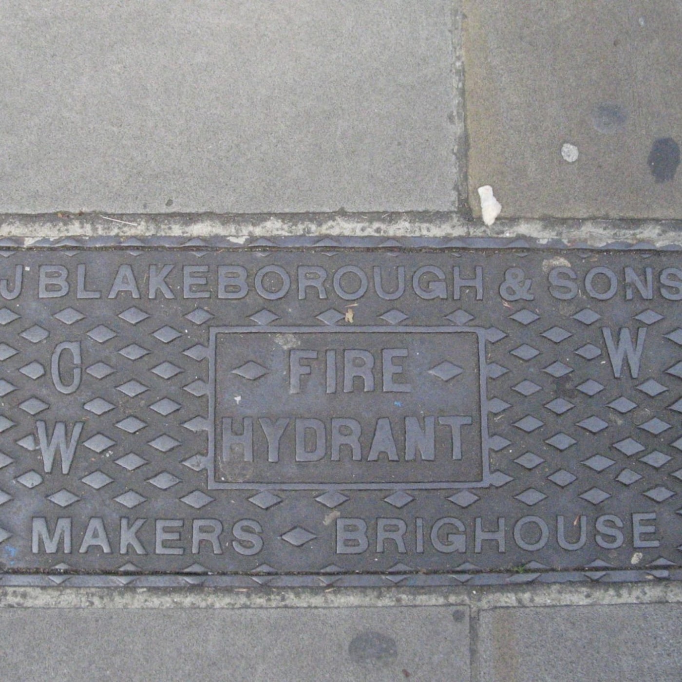 Na tomto exempláři litinového poklopu dominuje reliéfní text, který jasně identifikuje jeho výrobce a účel. Geometrický  in London, United Kingdom — CoverSpot