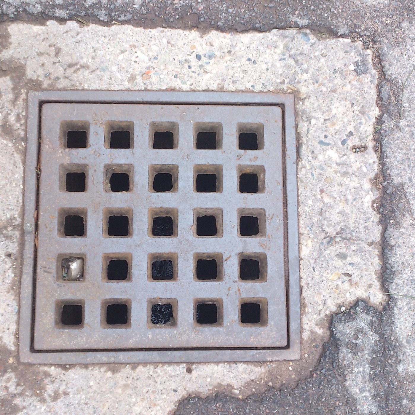 Mřížka pětadvaceti čtvercových otvorů dominuje centrálnímu vizuálnímu poli, uspořádaná v matici 5x5. Tento exemplář měst — CoverSpot