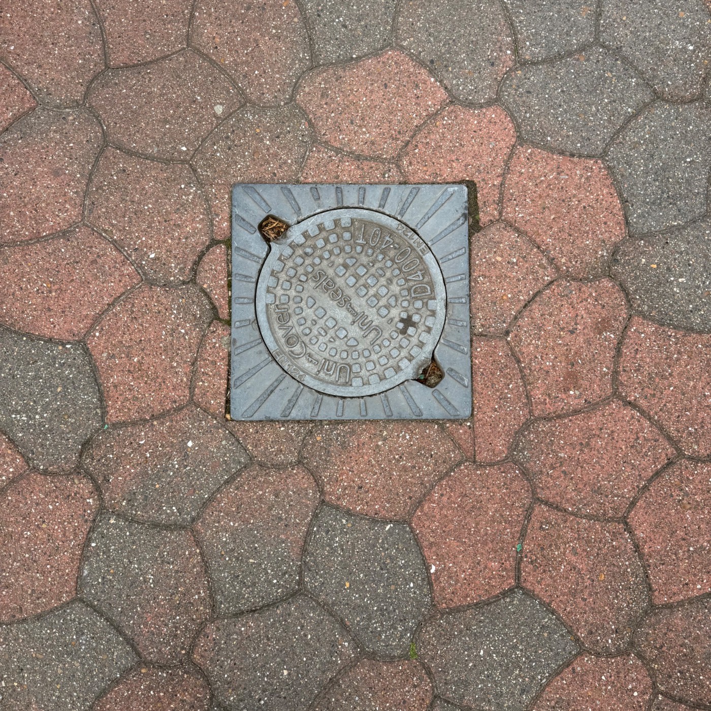 Kruhová textura s pravidelným rastrem čtverců dominuje centrálnímu prvku této dlažby, nesoucímu označení 'Uni-seals' a k in Billund, South Denmark, Denmark — CoverSpot