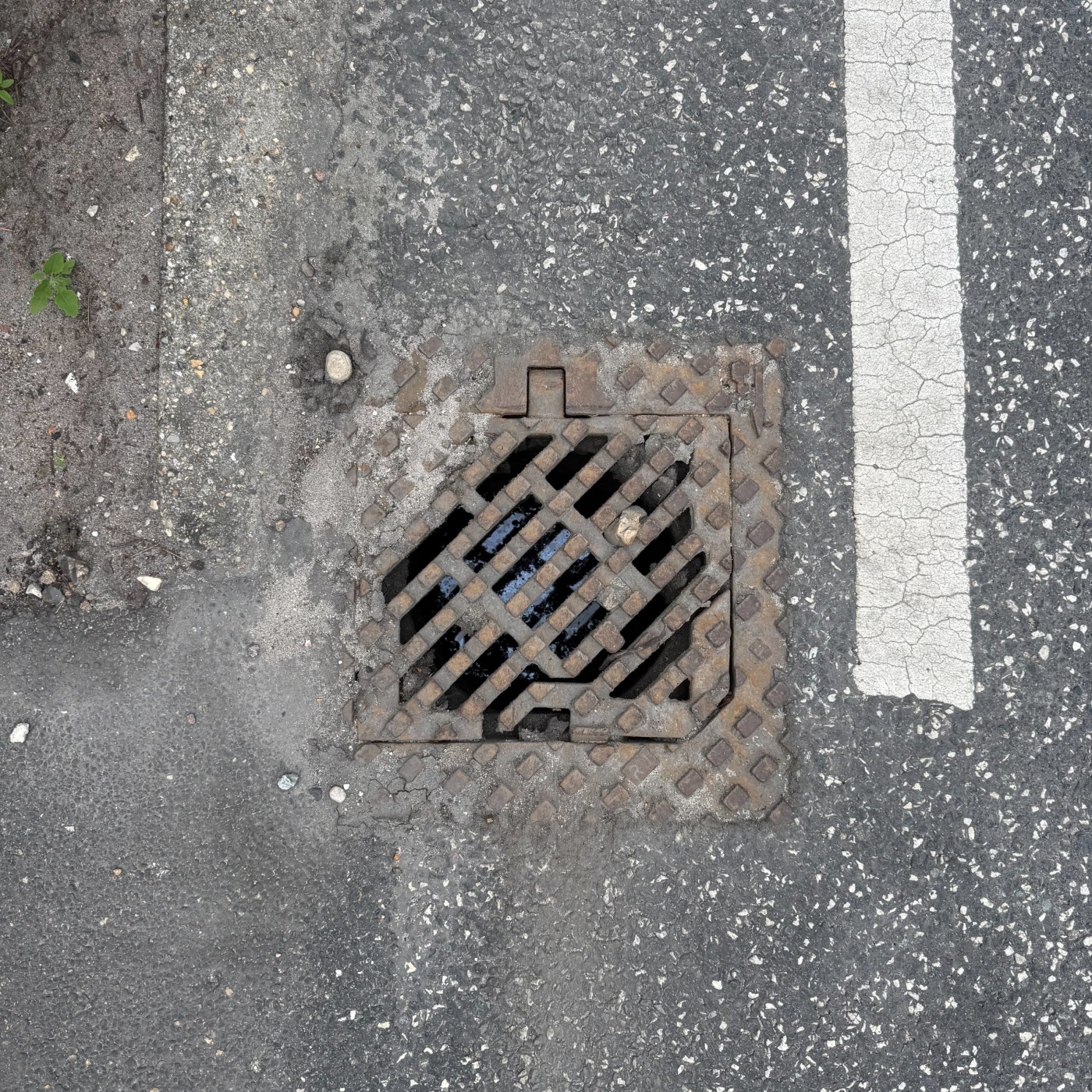 Na asfaltovém povrchu, vedle popraskané bílé čáry, se nachází čtvercová mříž s výrazným diagonálním a kosočtvercovým vzo in Billund, South Denmark, Denmark — CoverSpot