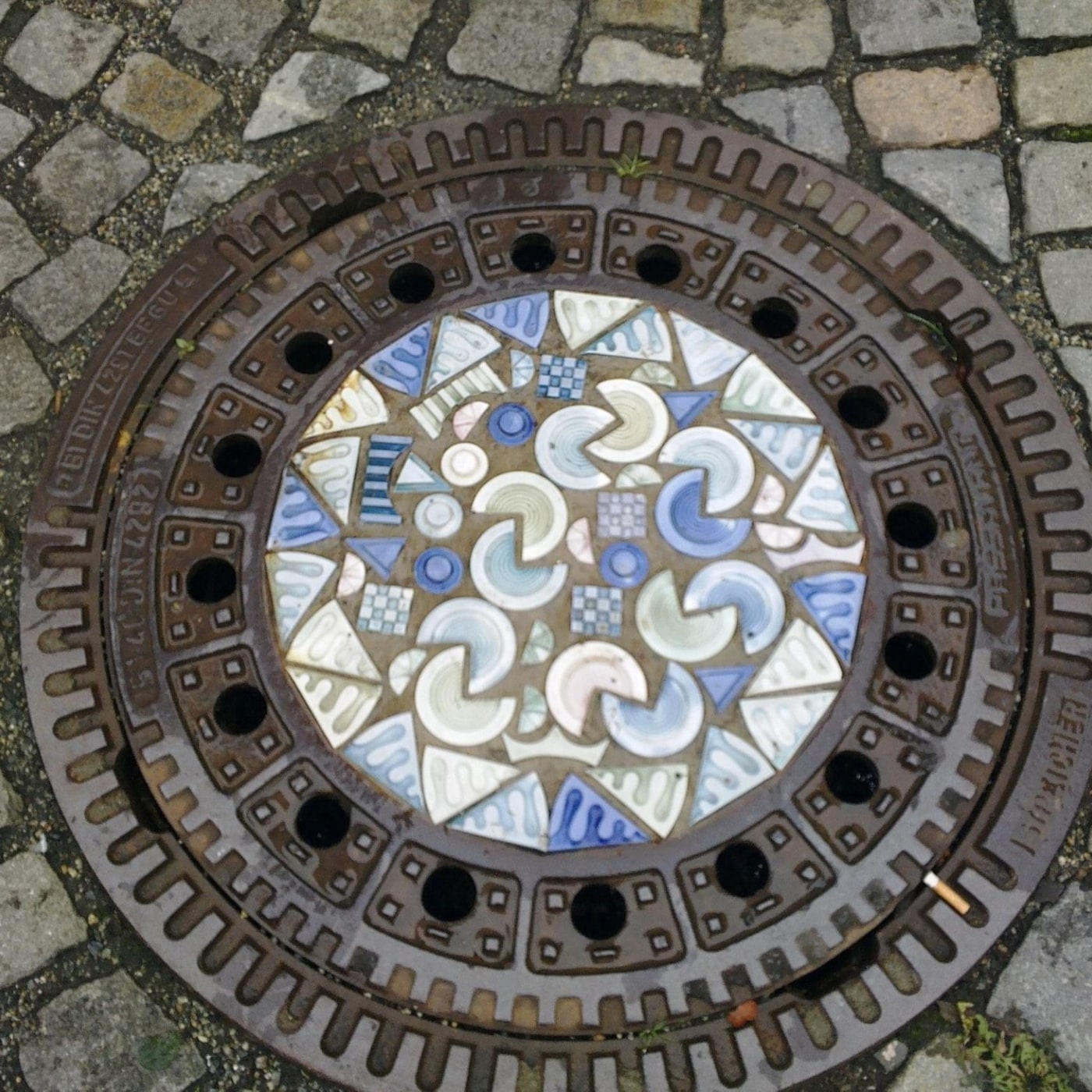 Centrální mozaika tohoto exempláře vykazuje komplexní geometrický vzor, tvořený fragmenty keramiky v odstínech modré, ze in Selb, Germany — CoverSpot