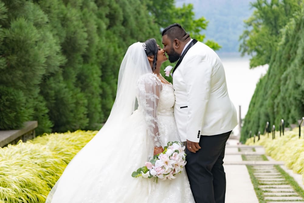 Bride and groom kissing on a garden path at golden hour
