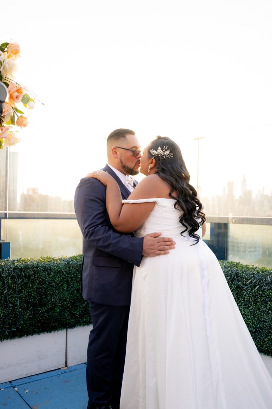 Couple kissing on a rooftop with the city skyline behind them