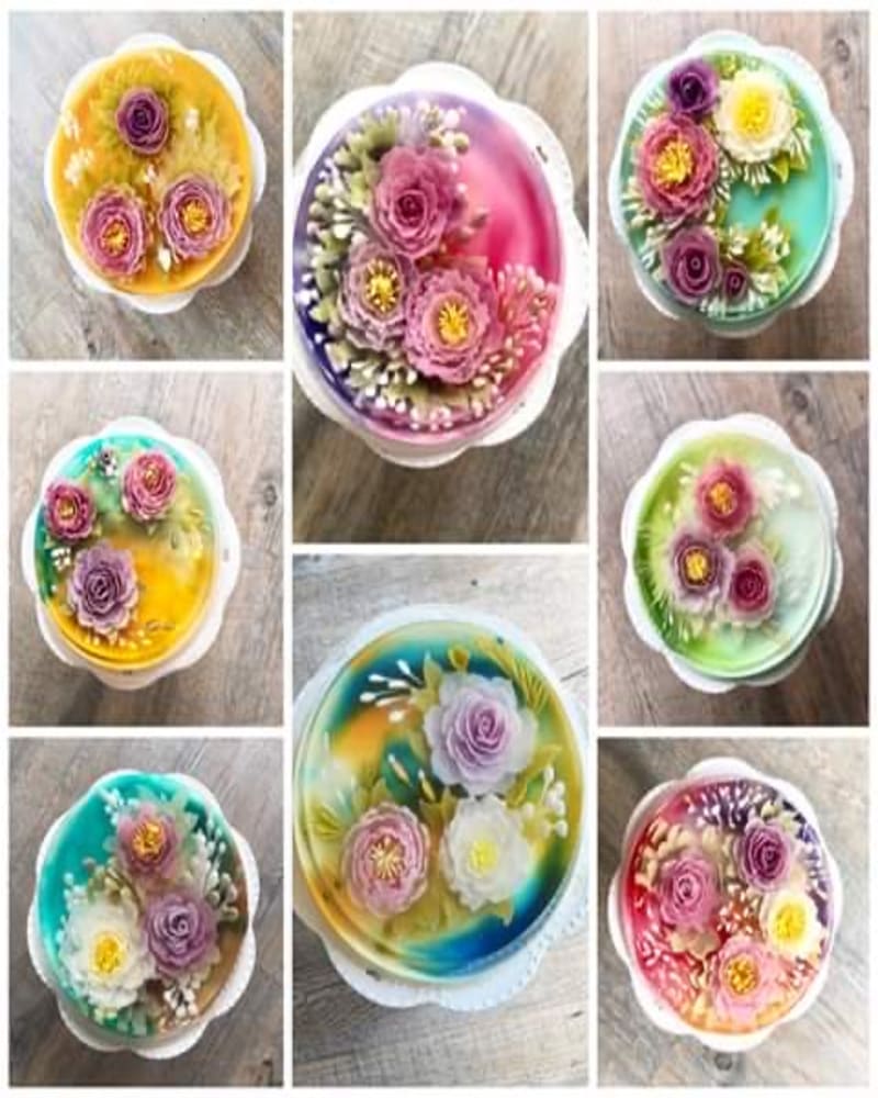 An array of translucent, encapsulation-style 3D jelly art cakes displaying vibrant internal floral structures like peonies and roses, crafted using precision needle-injection tools during an international culinary program.