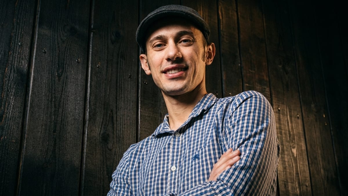Shopify chief executive Tobi Lutke in a flat cap and checked shirt against a timber wall
