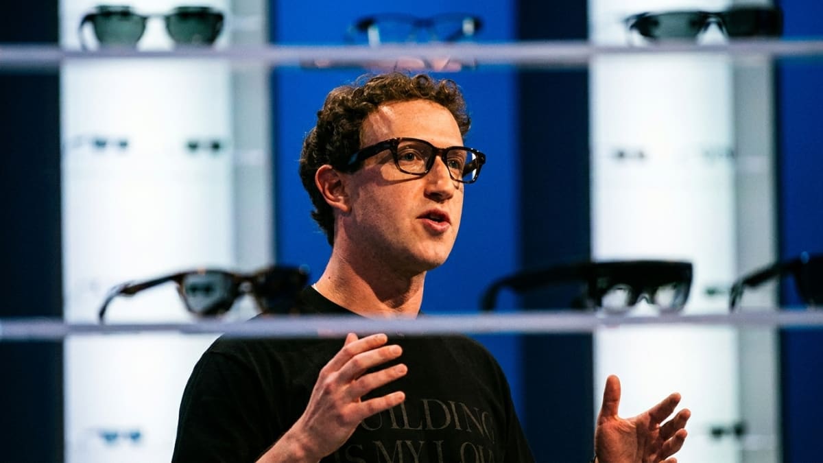 Meta chief executive Mark Zuckerberg speaking on stage in front of shelves of smart glasses