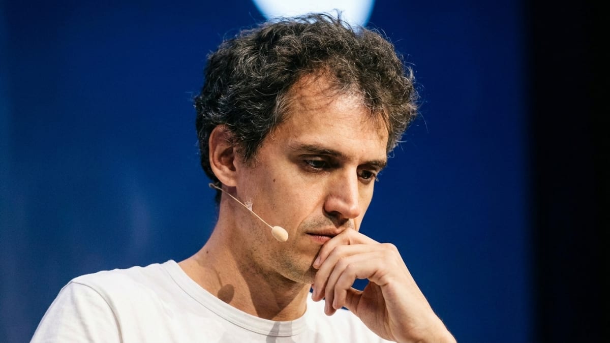 Mistral AI chief executive Arthur Mensch listening on stage at a technology conference, hand to his chin