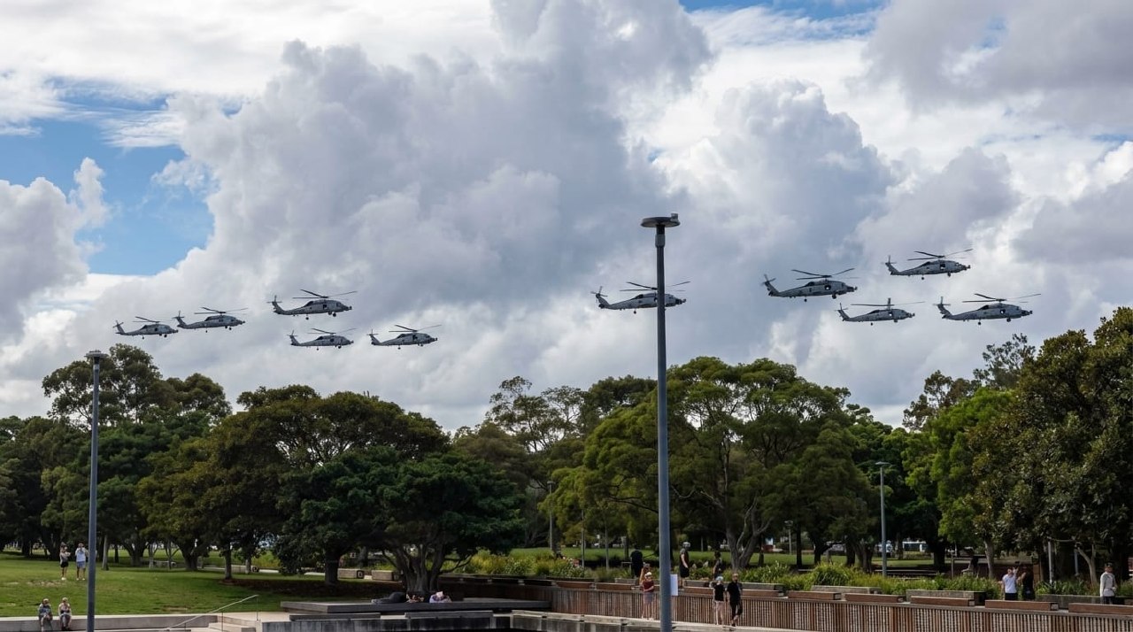 Ten MH-60R Seahawk helicopters flying in formation over a Sydney park as spectators watch from below during Exercise Kakadu 2026