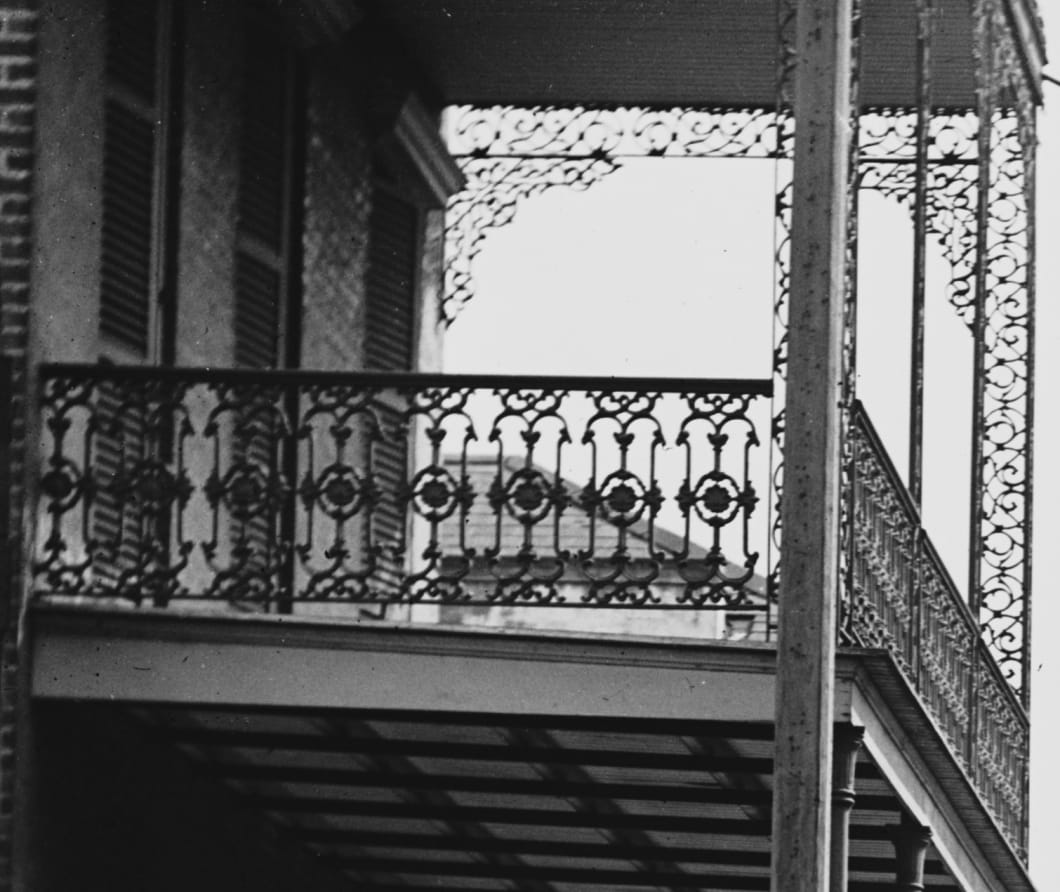 Detail from the plate: the cast-iron gallery with lacework railings on the two-story building
