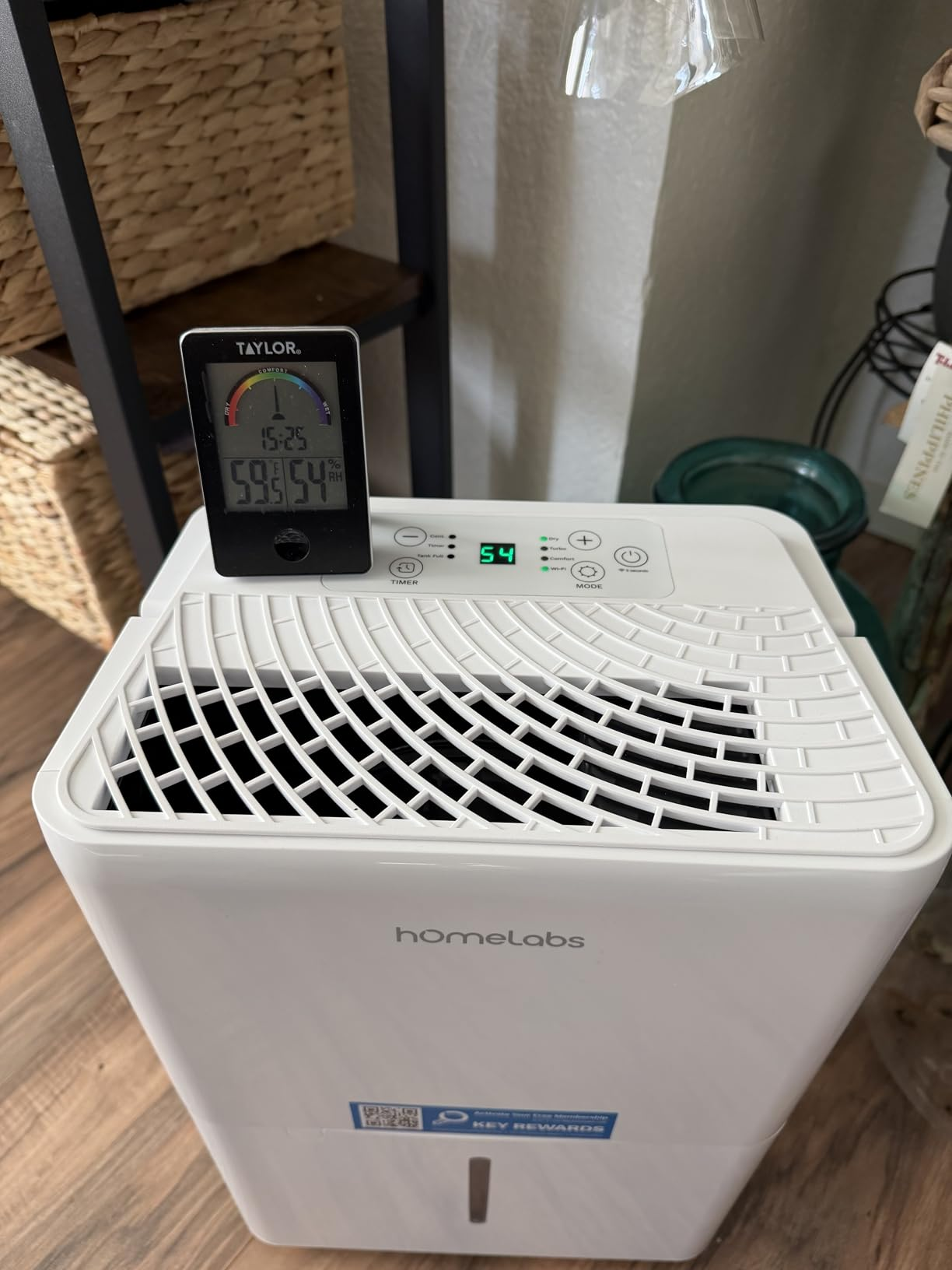 Built-in digital hygrometer on the hOmeLabs dehumidifier showing 54% humidity, matching the external Taylor hygrometer on top