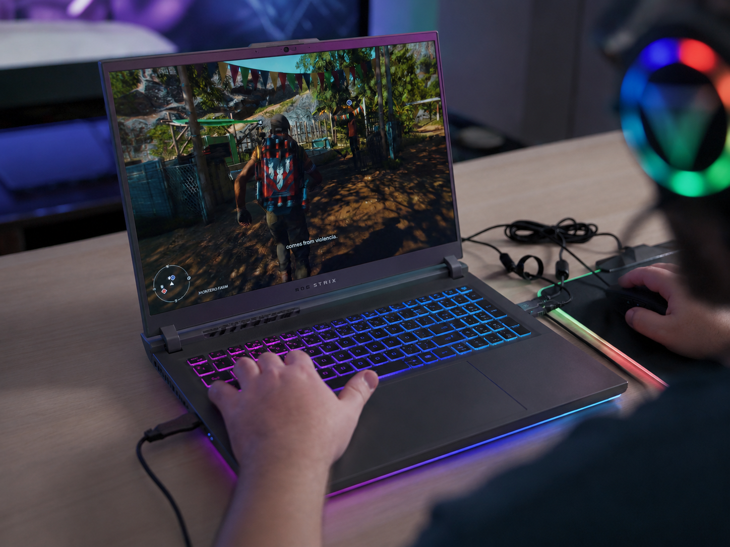 A gaming laptop with RGB keyboard illumination on a dark desk