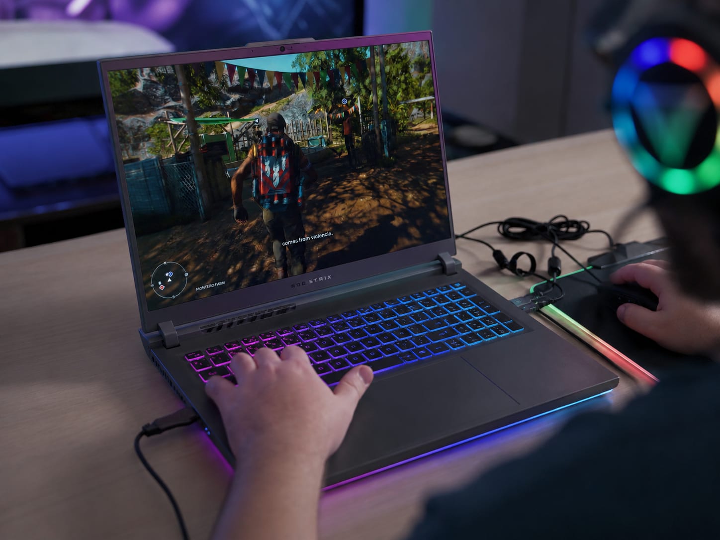A gaming laptop with RGB keyboard illumination on a dark desk