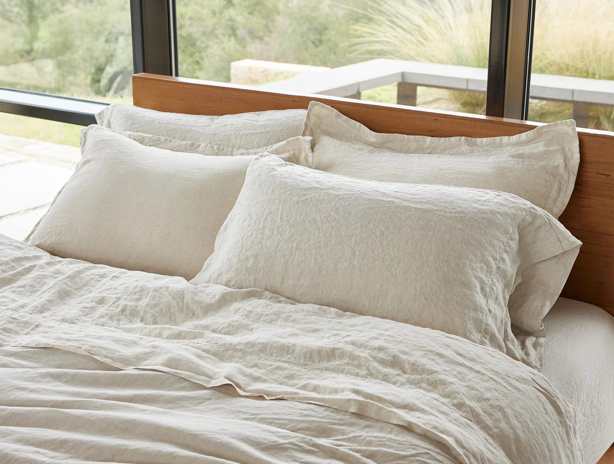 Folded stacks of bamboo, percale, and linen sheets side by side