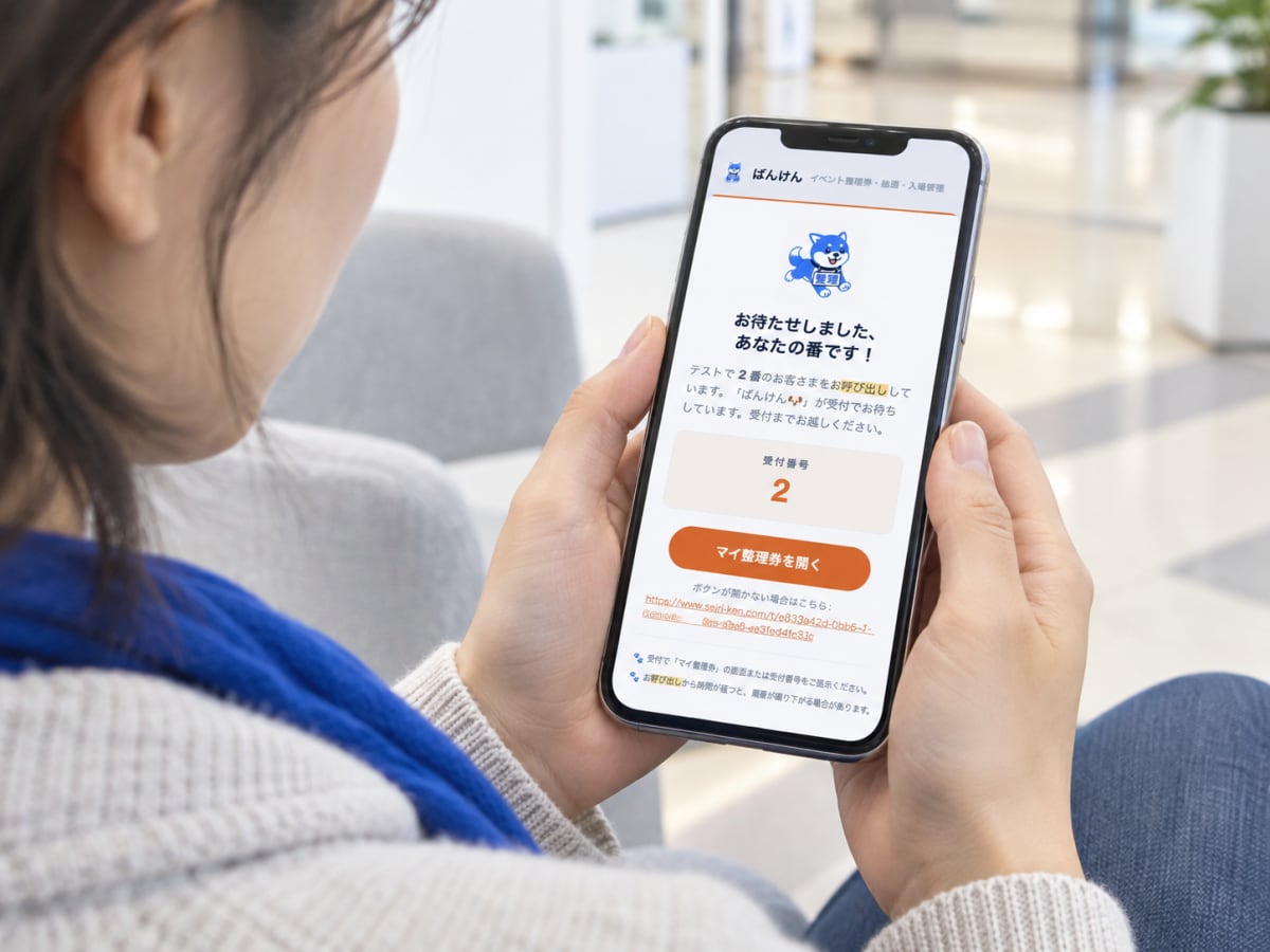 来場者が「あなたの番です」と表示されたスマートフォンの呼び出し画面を確認している様子