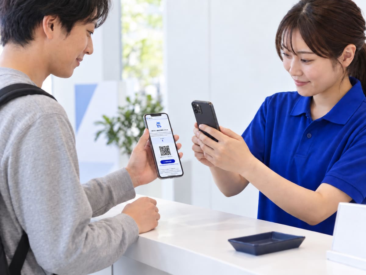受付スタッフが来場者の整理券QRを自分の端末のカメラで読み取っている様子