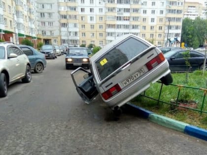 Пожилая омичка на «Ладе» не смогла разъехаться с другим авто во дворе, и ее машина повисла на заборе — соцсети