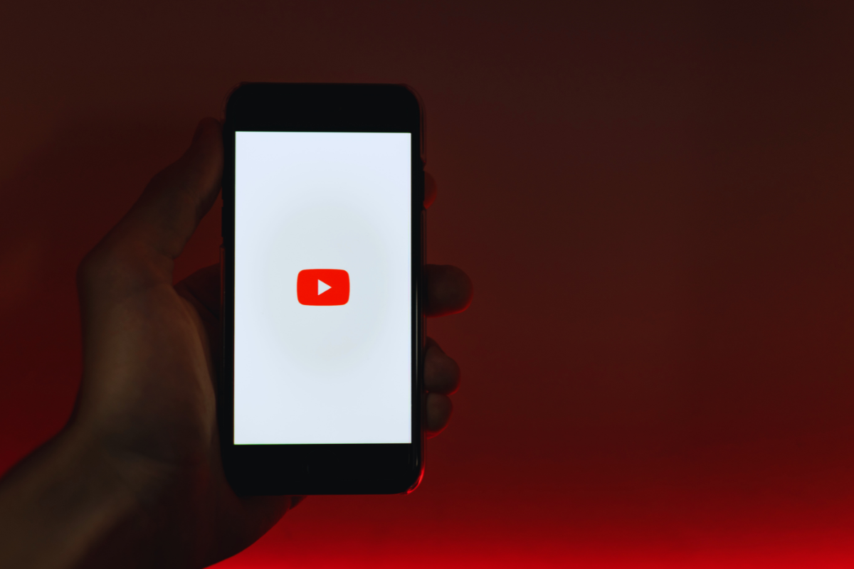 une main tenant un smartphone qui lance l’application youtube - creator academy