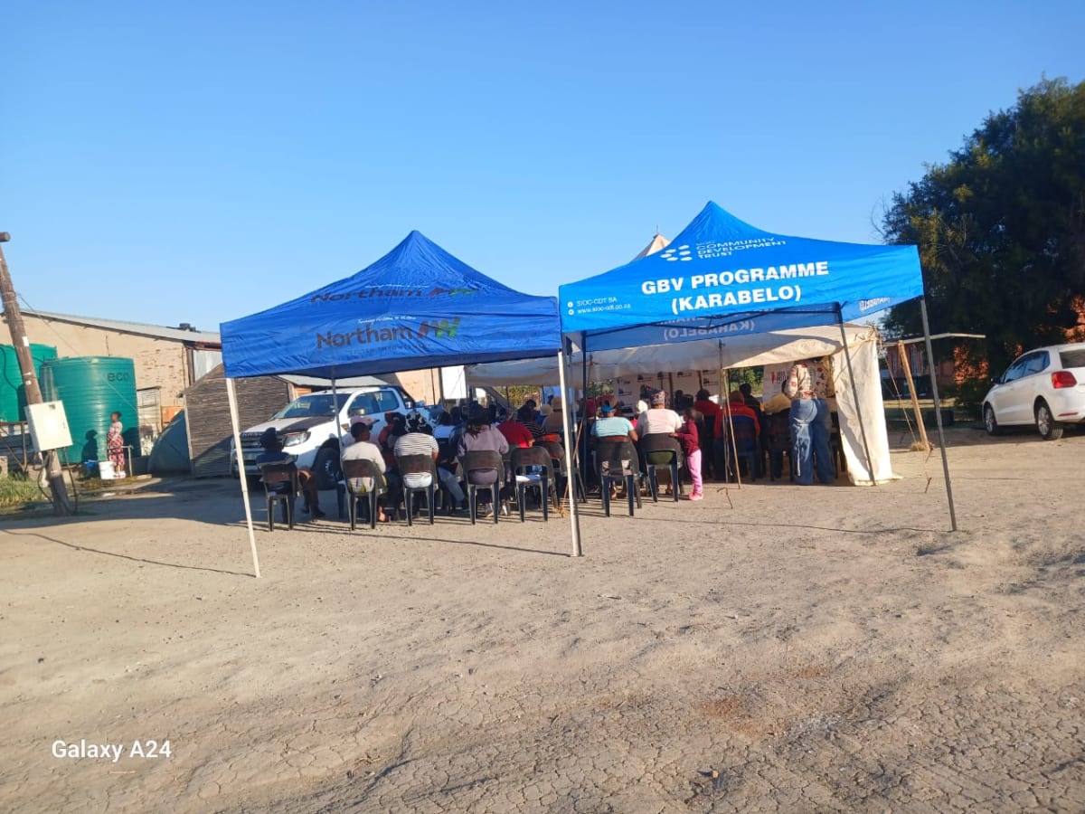 Branded GBV Programme (Karabelo) gazebos set up in a community yard with a session underway.
