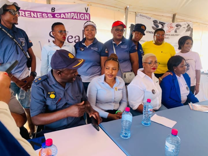 Officials seated at a table addressing attendees at a gender-based violence awareness campaign.