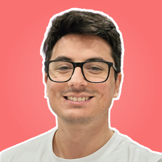 Portrait of Pedro La Rosa smiling against a red background.