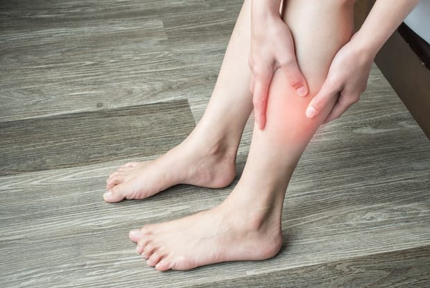 a person grasping their leg in pain. width=