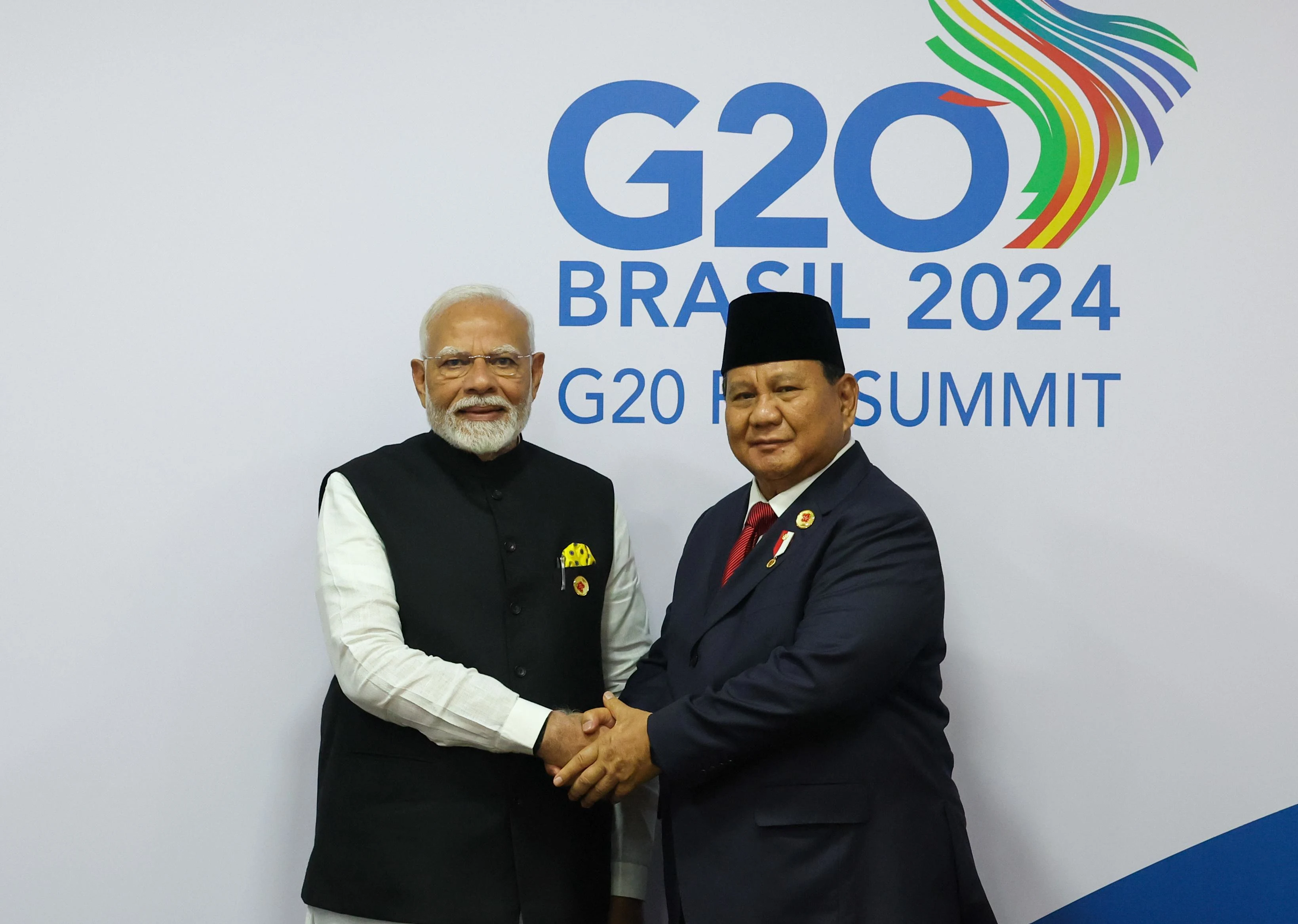 "Indian Prime Minister Narendra Modi shakes hands with Indonesian President Prabowo Subianto during the G20 Summit, with the G20 Brasil 2024 logo displayed in the background, symbolizing India-Indonesia diplomatic cooperation."