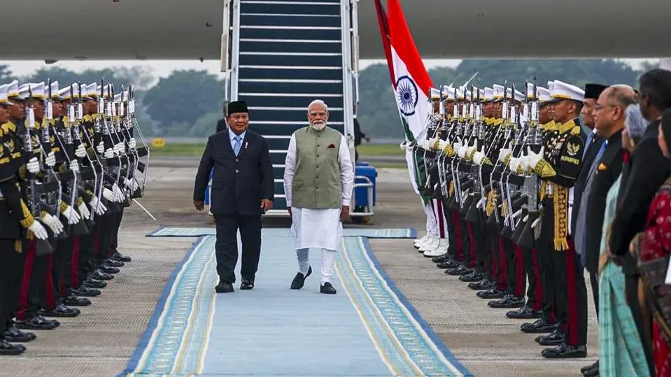 "Prime Minister Narendra Modi walks alongside Indonesian President Prabowo Subianto during a ceremonial guard of honour at the airport, highlighting the official welcome for Modi's state visit to Indonesia."