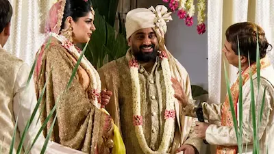 "Anshula Kapoor and her groom share a joyful moment during their traditional Mumbai wedding ceremony, surrounded by family members in an elegant floral setting."