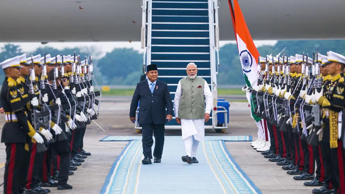 "Prime Minister Narendra Modi walks alongside Indonesian President Prabowo Subianto during a ceremonial guard of honour at the airport, highlighting the official welcome for Modi's state visit to Indonesia."