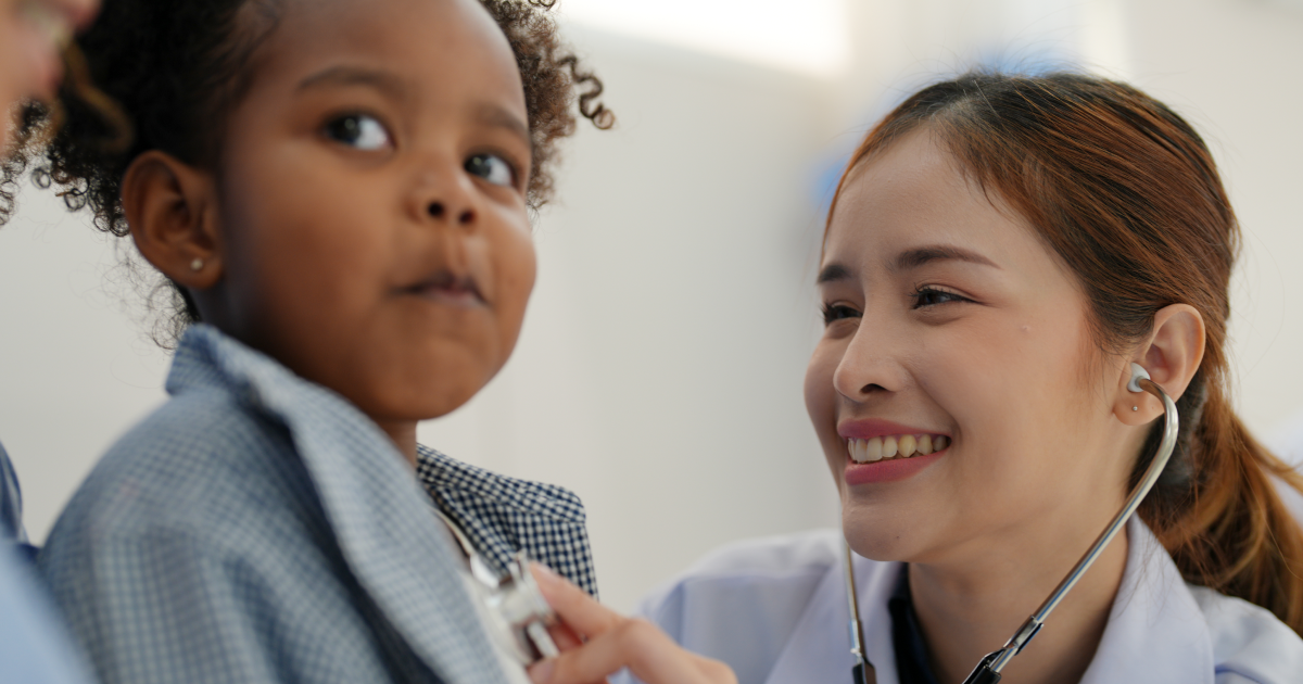 Pediatrician using a stethoscope to examine a young child during a checkup