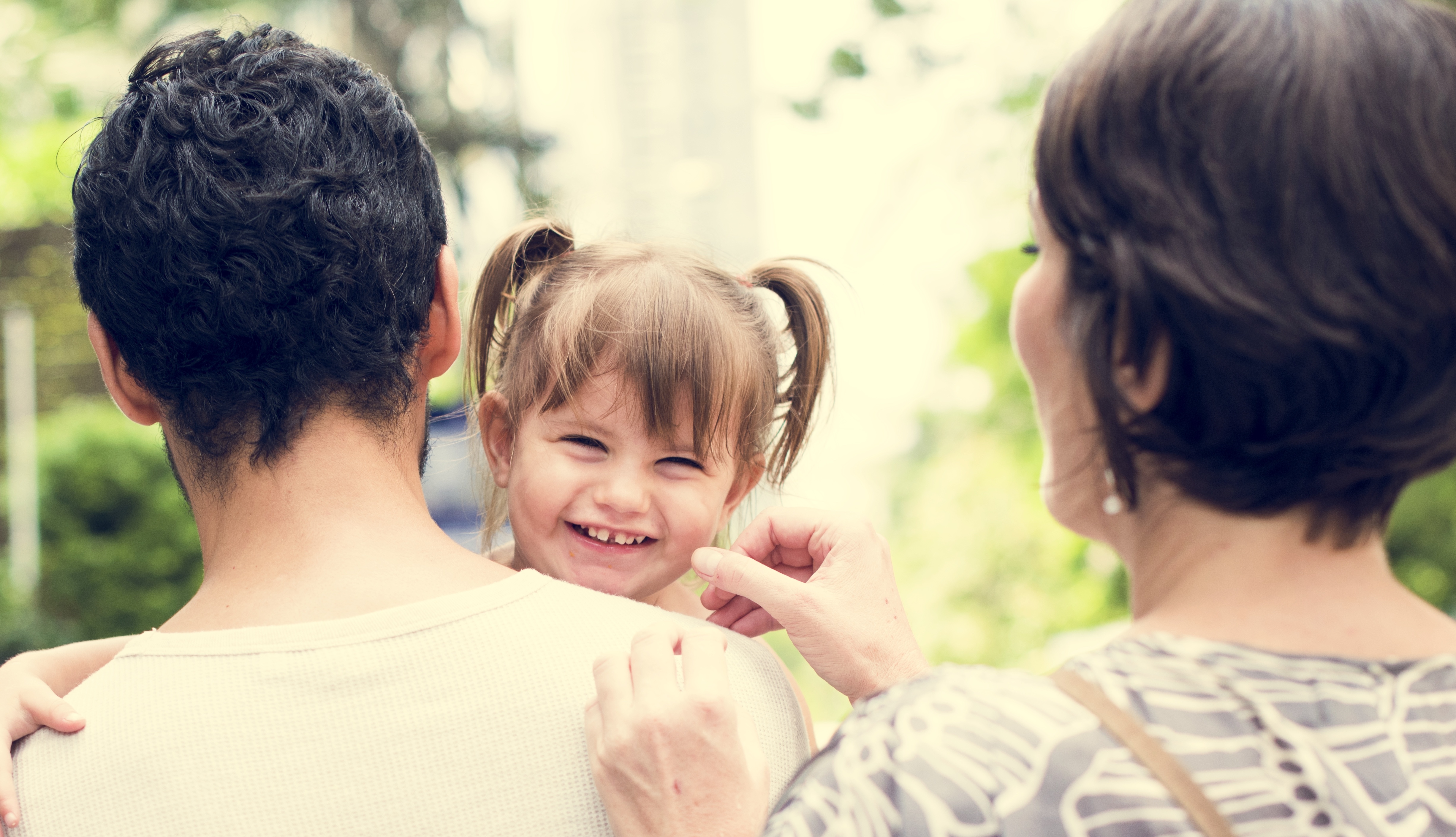 Young girl smiling with parents in a green park