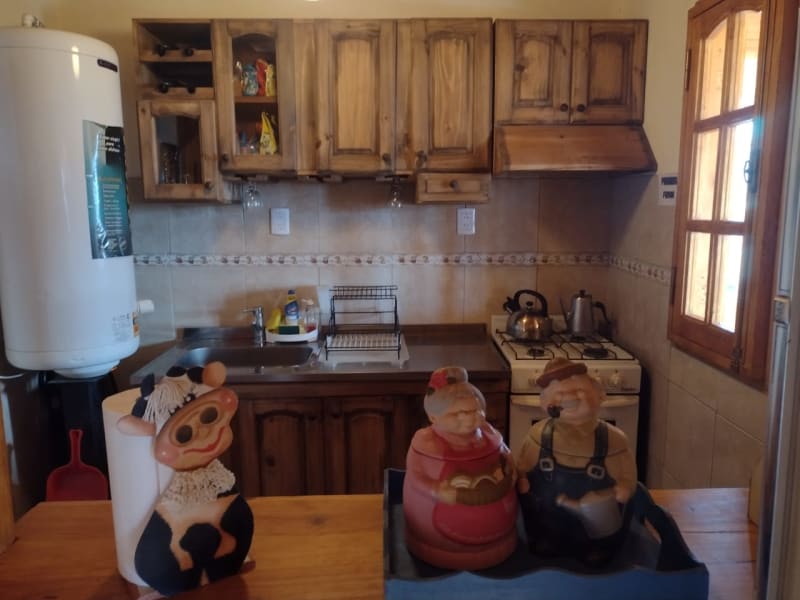 Cocina rústica totalmente equipada con muebles artesanales y vajilla en Cabaña Casa