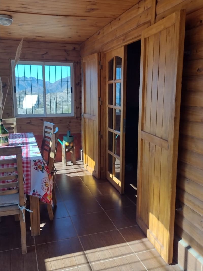 Comedor rústico con mesa familiar, paredes de madera y ventanales con vista a las montañas