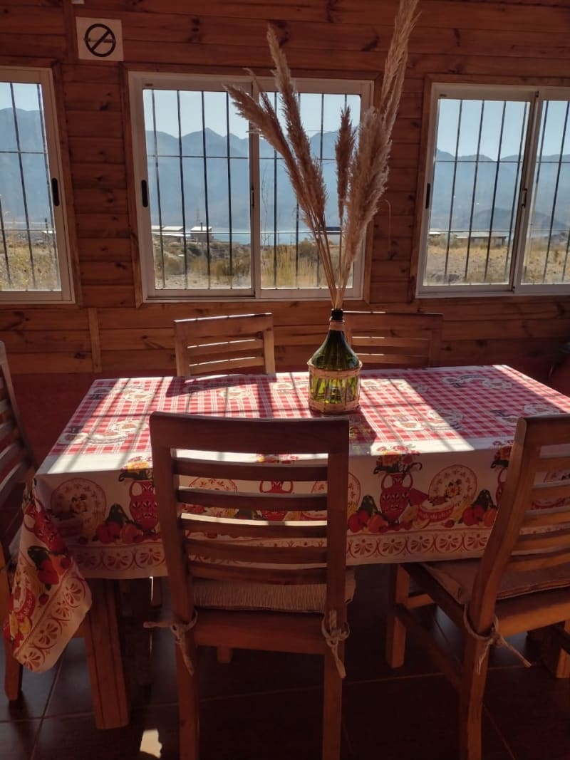 Mesa de comedor rústica con centro de flores secas y amplios ventanales con vista a la cordillera