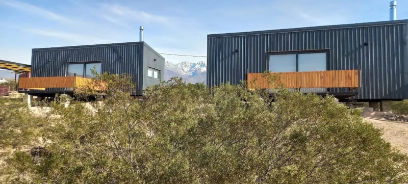 Cabañas contemporáneas con balcones de madera cálida elevadas entre arbustos autóctonos de jarilla