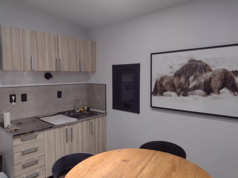 Mesa de comedor redonda con sillas de diseño moderno y cuadro de caballos salvajes en la pared