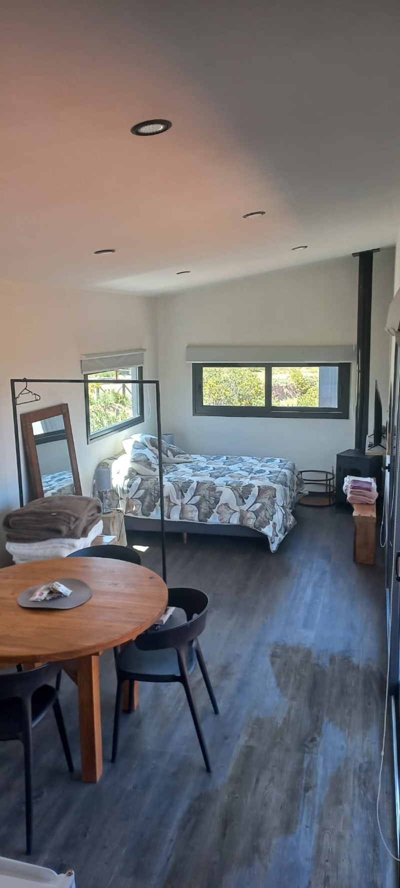 Espacio abierto integrado tipo loft con comedor, dormitorio con amplios ventanales y salamandra a leña