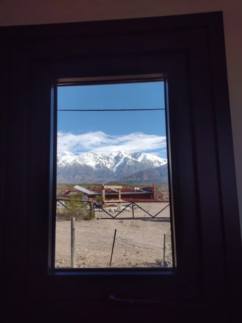 Ventanale enmarcando las cumbres nevadas de la Cordillera de los Andes y la estepa mendocina