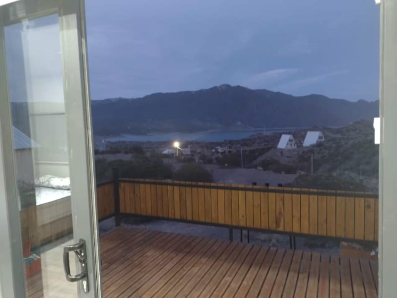 Vista panorámica al anochecer desde el deck con el lago Potrerillos y las luces del valle encendiéndose