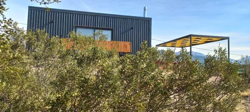 Cabaña modular integrada entre la vegetación serrana y arbustos autóctonos de jarilla con pérgola para vehículos
