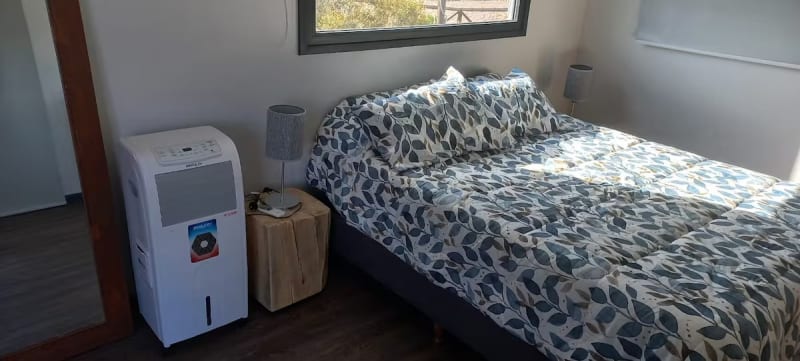 Habitación matrimonial luminosa con ventanales a la montaña, climatizador portátil y decoración cálida