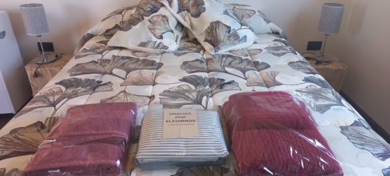 Juegos de toallas y toallones de alta densidad preparados sobre la cama con tarjeta de bienvenida