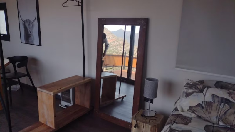Espejo de pie de cuerpo entero reflejando el deck y el lago, con perchero nórdico y estantería