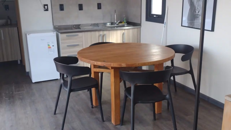 Mesa redonda de madera maciza con sillas modernas de diseño frente a la cocina